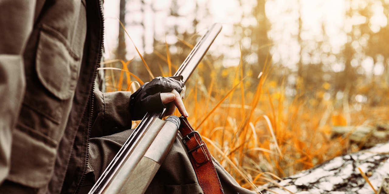 Hunter holding a hunting rifle in a field
