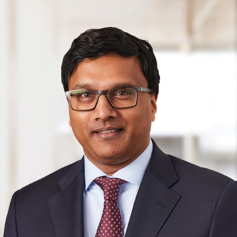 Professional headshot of Kiran Paruchuru  with abstract background.